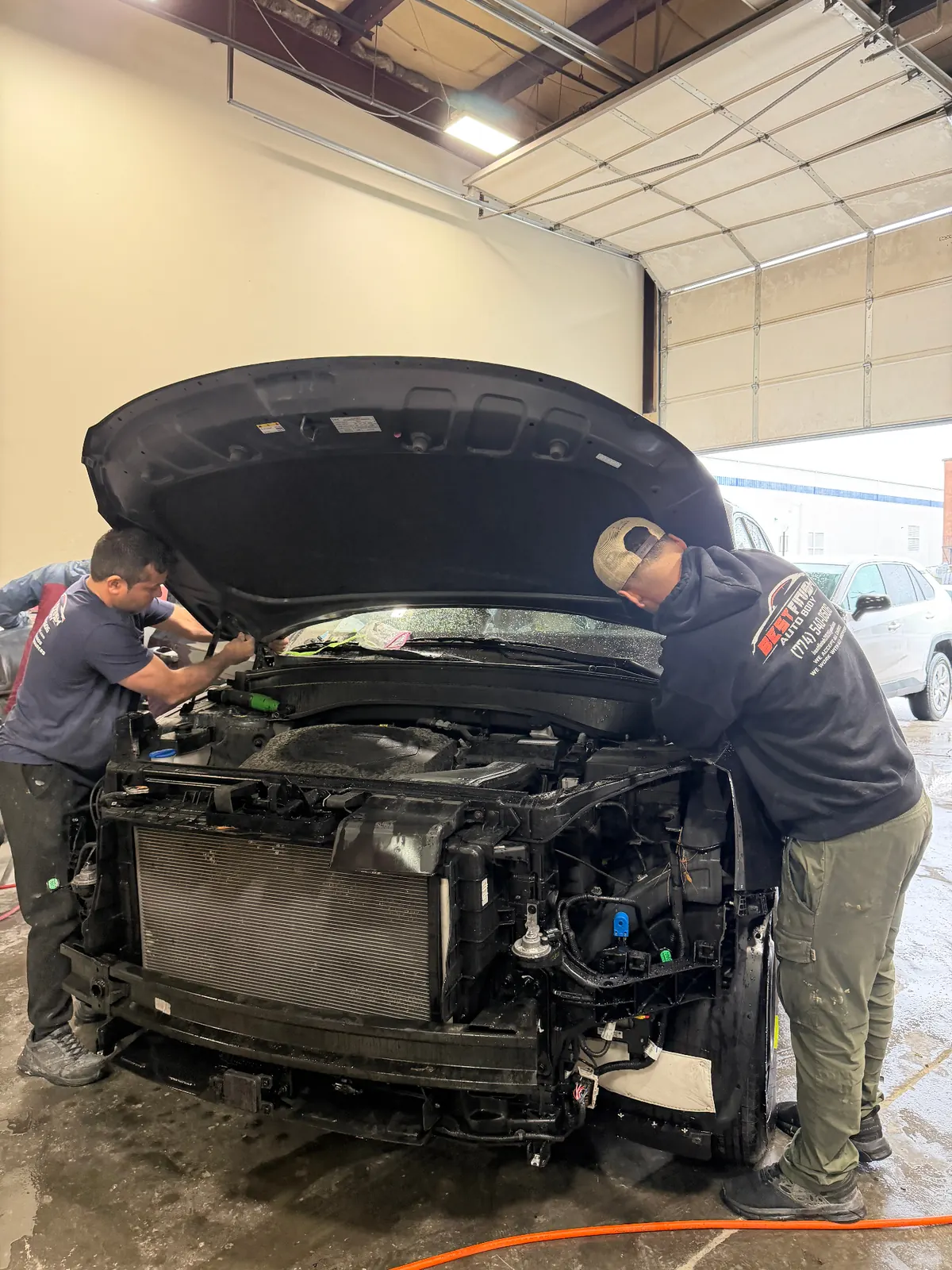 Best Finish technicians removing a hood for collision repair